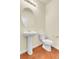 Clean powder room features a pedestal sink, toilet, modern lighting, and wood floors at 3310 Quicksilver Rd, Frederick, CO 80516