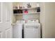 Efficient laundry room features a white washer and dryer, with shelving above for convenient storage at 9692 W Coco Cir # 304, Littleton, CO 80128