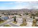 An aerial view shows a community with houses, trees, and the mountains in the distance at 15907 W 72Nd Dr, Arvada, CO 80007
