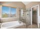 Elegant bathroom with a luxurious soaking tub and glass-enclosed shower, and a large bright window at 15907 W 72Nd Dr, Arvada, CO 80007