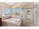 Well-lit bathroom featuring a soaking tub with tile surround, glass shower, and bright natural light at 15907 W 72Nd Dr, Arvada, CO 80007