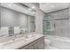 A spacious bathroom offers a large mirror, double sinks, and a glass-enclosed shower-tub combo at 15907 W 72Nd Dr, Arvada, CO 80007