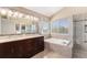 Bathroom featuring double vanity, a soaking tub, walk-in glass shower, and lots of natural light at 15907 W 72Nd Dr, Arvada, CO 80007