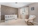 Cozy Bedroom with a white crib, decorative wall decals, and a comfortable armchair by the window at 15907 W 72Nd Dr, Arvada, CO 80007