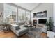 Bright living room with large windows, a fireplace, a gray sofa, and stylish decor at 15907 W 72Nd Dr, Arvada, CO 80007