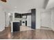 Clean kitchen with white appliances and black cabinetry, with view to bath and exterior door at 5250 S Huron Way # 3-205, Littleton, CO 80120