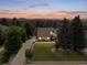 Lovely aerial view of home with mature landscaping, a long drive, and mountain views at sunset at 1025 S Butler Way, Lakewood, CO 80226