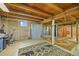 Unfinished basement with exposed wood beams, concrete walls, and colorful rugs at 1335 S Kio St, Watkins, CO 80137