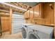Functional laundry area features washer, dryer, utility tub, and storage cabinets at 1335 S Kio St, Watkins, CO 80137