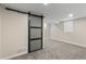 Finished basement featuring gray carpet, neutral paint, sliding barn door and view of another room at 2230 Jamaica St, Aurora, CO 80010