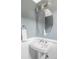 Bathroom with pedestal sink, oval mirror, and modern lighting fixtures at 9124 E 29Th Pl, Denver, CO 80238
