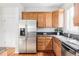 Well-lit kitchen with stainless steel refrigerator and wood cabinets at 9124 E 29Th Pl, Denver, CO 80238