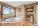 Bright bathroom featuring a soaking tub with scenic views and decorative curtains at 8518 High Ridge, Castle Pines, CO 80108