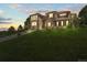 The exterior of the home is set back with a gently sloping front lawn with dark brown and stone color palette at 8518 High Ridge, Castle Pines, CO 80108