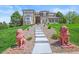 Daytime front exterior of an elegant home with lush landscaping, mature trees, and an impressive front walkway at 8518 High Ridge, Castle Pines, CO 80108