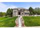 Beautiful front exterior of a multi-story home with a lush lawn, stone accents, and elegant landscaping at 8518 High Ridge, Castle Pines, CO 80108