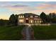 The front exterior of the home is well lit during twilight showcasing the stone accents and manicured front lawn at 8518 High Ridge, Castle Pines, CO 80108