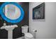 Stylish powder room with a vessel sink, a round mirror with a blue frame, and modern fixtures at 3564 Doubletrack Ln, Castle Rock, CO 80108
