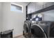 Modern laundry room featuring front load washer and dryer set with gray cabinets and shelving for optimal storage at 3564 Doubletrack Ln, Castle Rock, CO 80108