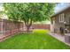 Beautifully landscaped backyard features green lawn, stone accents and mature shade tree at 5007 S Richfield Cir, Aurora, CO 80015