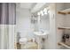 Cozy bathroom featuring a pedestal sink, white tiling and bright vanity lighting at 5007 S Richfield Cir, Aurora, CO 80015