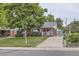 Charming brick home featuring a well-manicured lawn, covered porch, and spacious driveway at 1824 S Columbine St, Denver, CO 80210