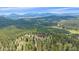 Breathtaking aerial view showcasing lush forestry and scenic mountain views with a house in the distance at 31231 Red Hawk Trl, Conifer, CO 80433