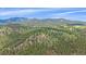 Beautiful aerial view of the home surrounded by lush greenery, mountains, and blue skies at 31231 Red Hawk Trl, Conifer, CO 80433