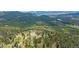 Expansive aerial shot of the home on acreage surrounded by lush forestry and mountainous views at 31231 Red Hawk Trl, Conifer, CO 80433
