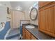 Well-lit bathroom with round mirror over the sink and shower with blue wainscoting at 31231 Red Hawk Trl, Conifer, CO 80433