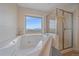 Inviting primary bathroom featuring a jetted tub, glass-enclosed shower, and scenic views at 31231 Red Hawk Trl, Conifer, CO 80433