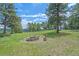 Outdoor fire pit area surrounded by seating in a verdant green yard under a blue sky at 31231 Red Hawk Trl, Conifer, CO 80433