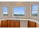 Bright kitchen featuring wood cabinetry, white appliances, and a large window offering stunning mountain views at 31231 Red Hawk Trl, Conifer, CO 80433