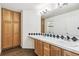 Bathroom featuring double sinks, wood cabinets and a large mirror at 5789 S Jay St, Littleton, CO 80123