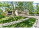 View of the home's front yard and brick-accented three-car garage, showcasing its curb appeal at 5789 S Jay St, Littleton, CO 80123