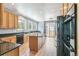 Kitchen with wood cabinets, black countertops, center island, and stainless steel appliances at 5789 S Jay St, Littleton, CO 80123