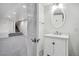 Modern white bathroom with a large mirror, vanity, and access to the carpeted basement at 1401 S Clarkson St, Denver, CO 80210