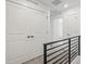Hallway featuring white doors, a black metal railing, and neutral carpet leading to other rooms at 2036 S Holly St # 4, Denver, CO 80222