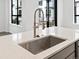 The island kitchen sink features a modern spring faucet and quartz countertops at 2036 S Holly St # 4, Denver, CO 80222
