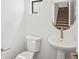 Bright powder room with pedestal sink, modern fixtures, and an oval mirror reflecting the carpeted stairs at 2036 S Holly St # 4, Denver, CO 80222