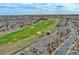 An aerial view showcases townhomes bordering a lush golf course with sand traps and city and mountain views beyond at 2875 Blue Sky Cir # 4-303, Erie, CO 80516