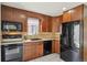 Features a window over the sink, tiled back splash, wood cabinets, and black appliances at 9338 W Utah Pl, Lakewood, CO 80232