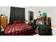 Spacious bedroom with a red and black plaid comforter, small fridge, and storage at 14444 E Colorado Dr # 204, Aurora, CO 80012