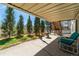 Covered patio overlooks lush green trees and landscaping with a relaxing lounge chair at 2462 W Peakview Ct, Littleton, CO 80120