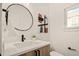 Modern half bathroom features a round mirror, stylish vanity, white quartz countertops, and unique fixtures at 1344 N Knox Ct, Denver, CO 80204