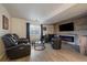 Entertainment area featuring leather seating, coffee tables, an electric fireplace, and brick accent wall at 7895 S Zante Ct, Aurora, CO 80016