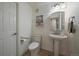 Cozy bathroom with pedestal sink, artwork, and convenient towel bar near the toilet and door at 7895 S Zante Ct, Aurora, CO 80016