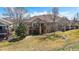 View of the home's backyard with a stone facade, covered patio, and lush green lawn at 7895 S Zante Ct, Aurora, CO 80016