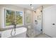 Bathroom featuring a soaking tub, glass shower, and views of the backyard at 20838 Parliament Ct, Parker, CO 80138
