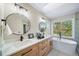 Bright bathroom featuring double sinks, wood cabinetry, a soaking tub and backyard views at 20838 Parliament Ct, Parker, CO 80138